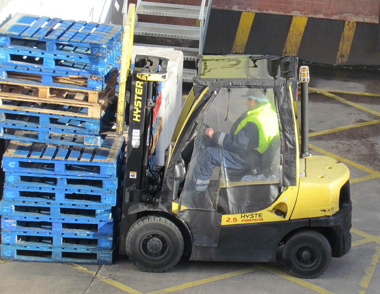 Carretilla elevadora transportando una pila de palés azules