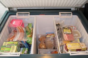Congelador horizontal abierto con alimentos congelados