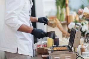 Manipulador de alimentos con guantes preparando comida en un puesto
