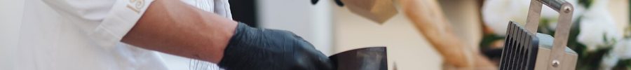 Manipulador de alimentos con guantes preparando comida en un puesto