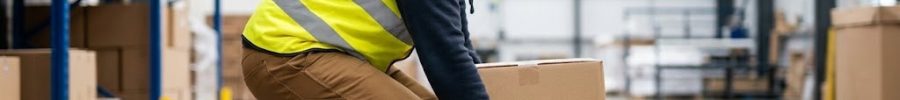 Mozo de almacén flexionando las rodillas con la espalda recta para levantar una caja