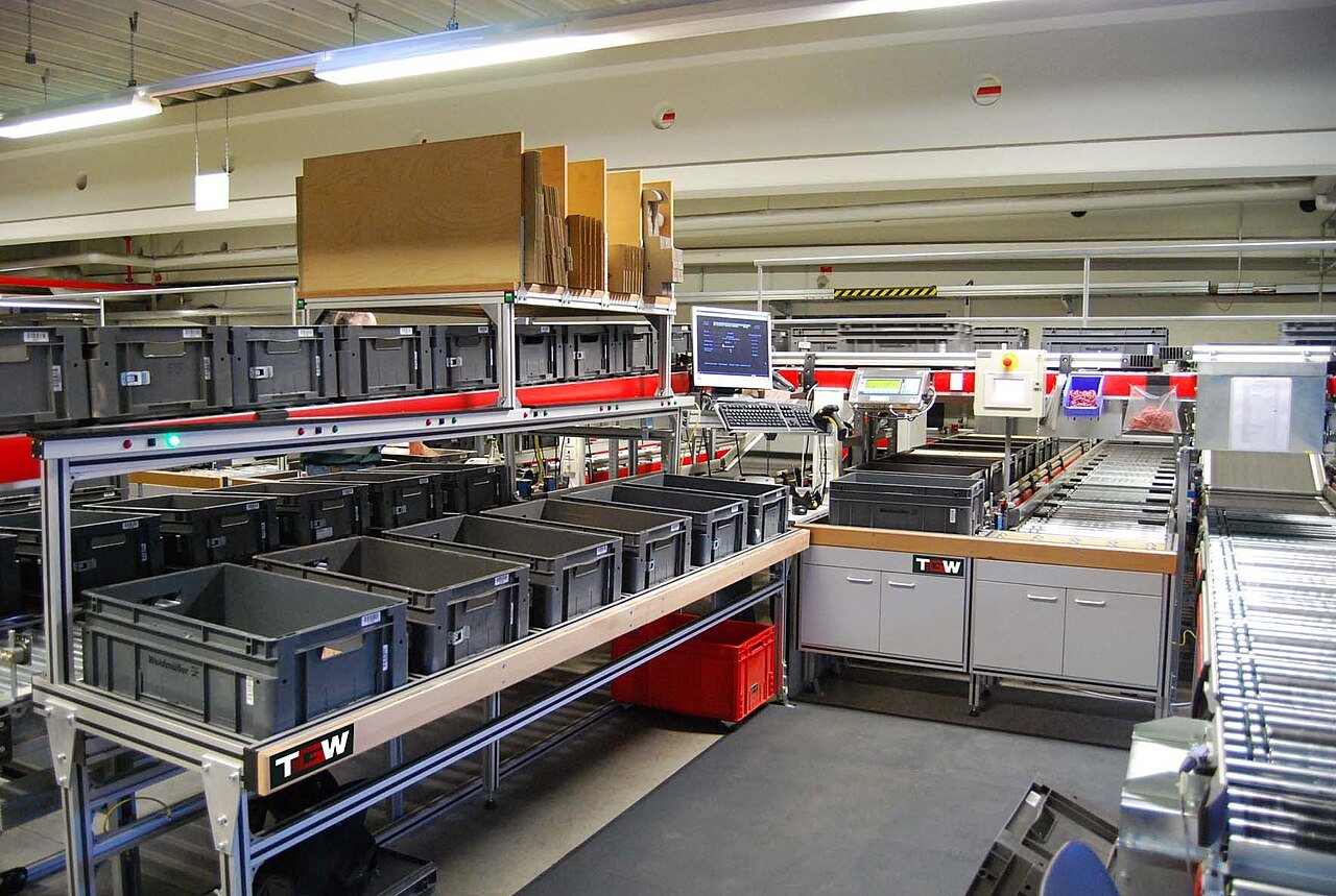 Estación de preparación de pedidos con cajas, mesa de trabajo y cinta transportadora