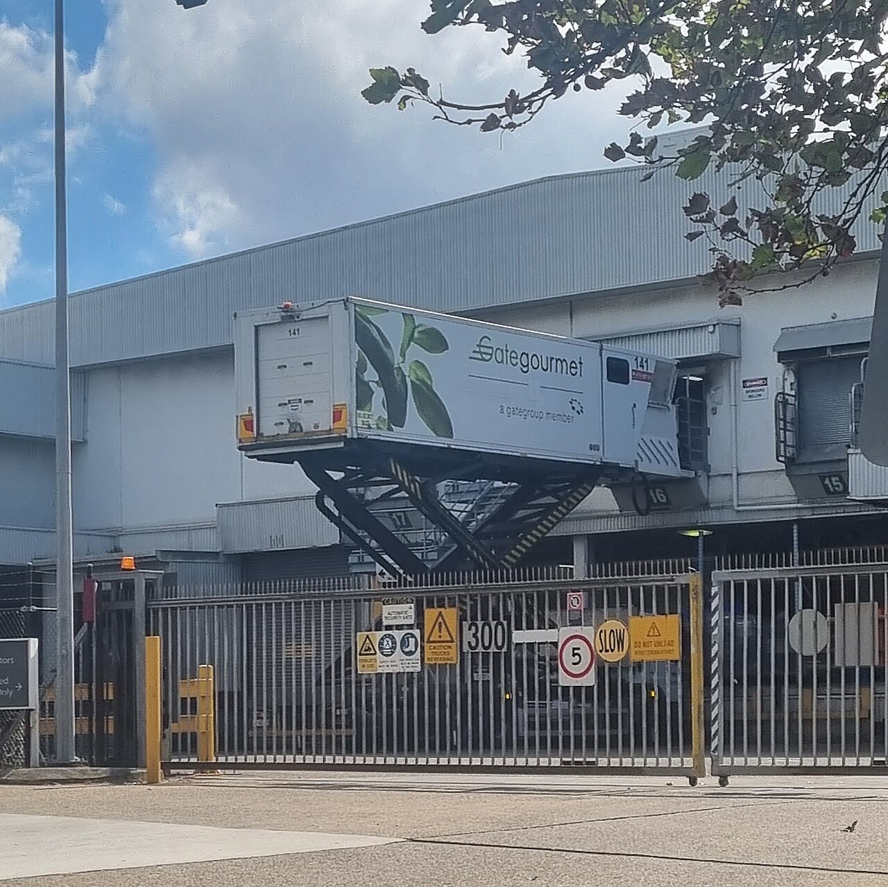 Muelle de carga con camión elevado junto a la puerta del almacén y señales de advertencia