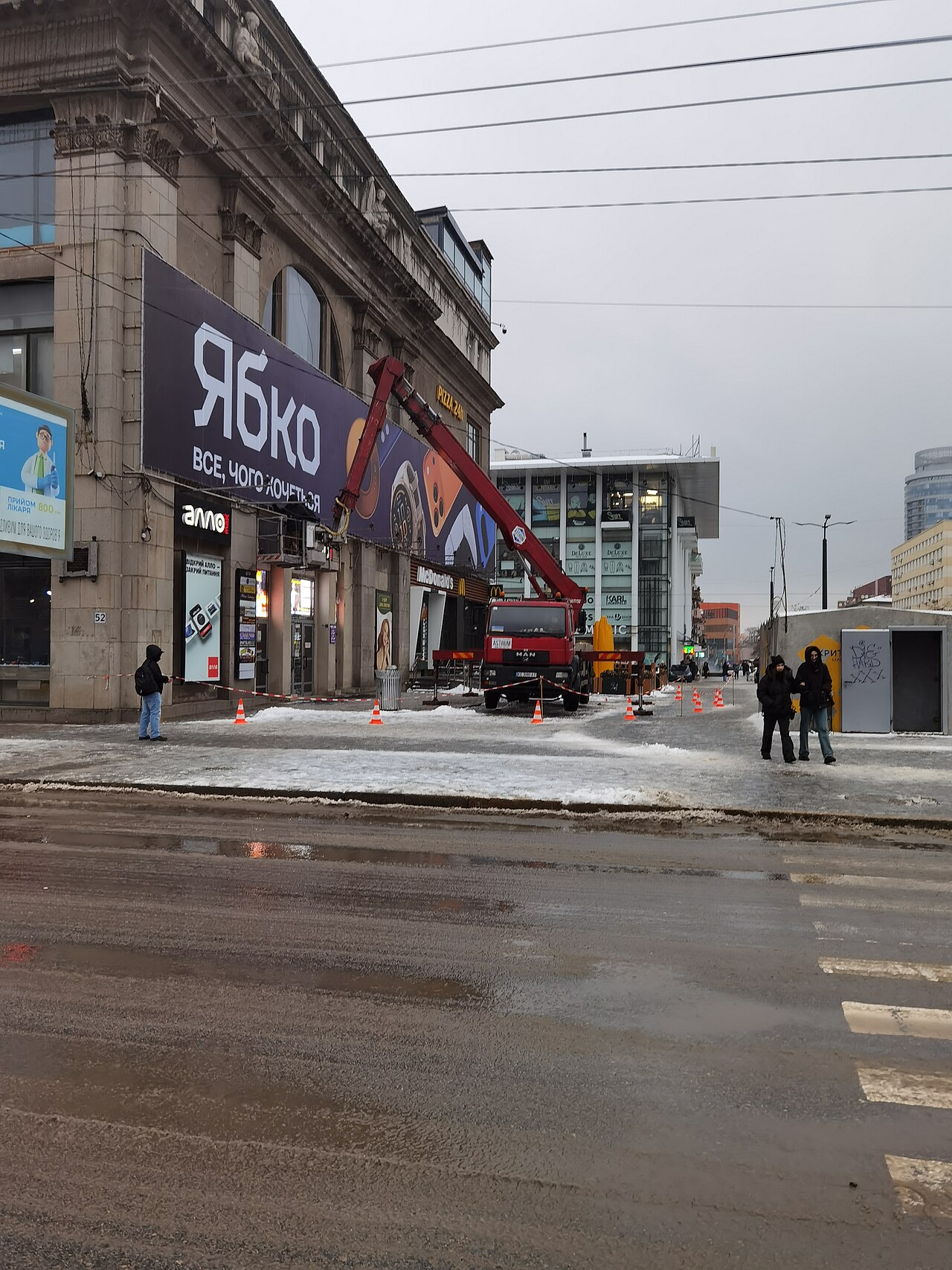 Camión con plataforma elevadora en la calle con la zona acotada con conos y cinta