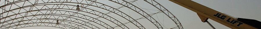 Plataforma elevadora de brazo telescópico con la cesta en altura junto a una estructura metálica