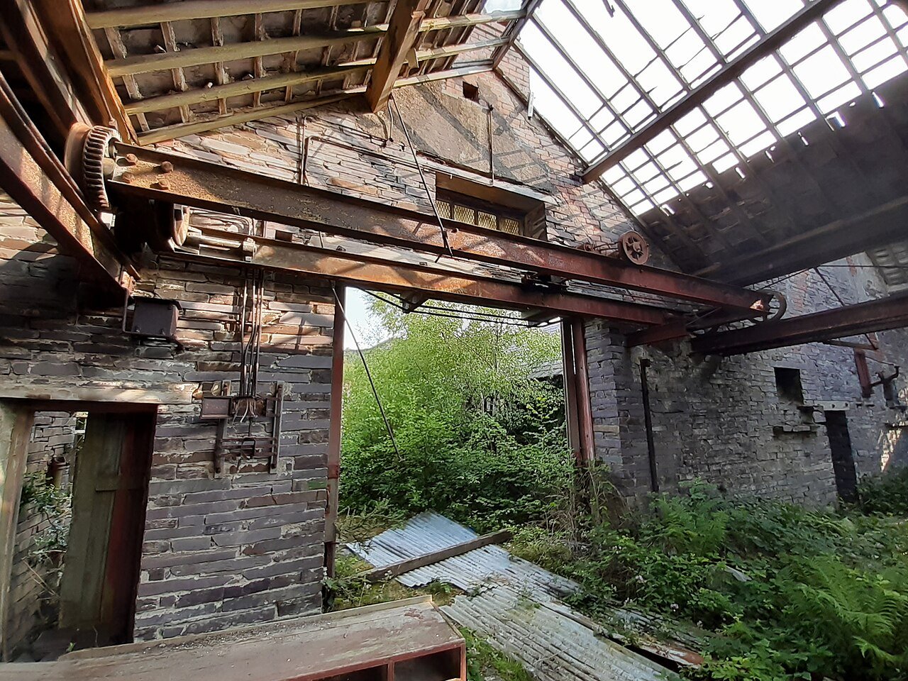Puente grúa antiguo con carro y polipasto en un taller abandonado