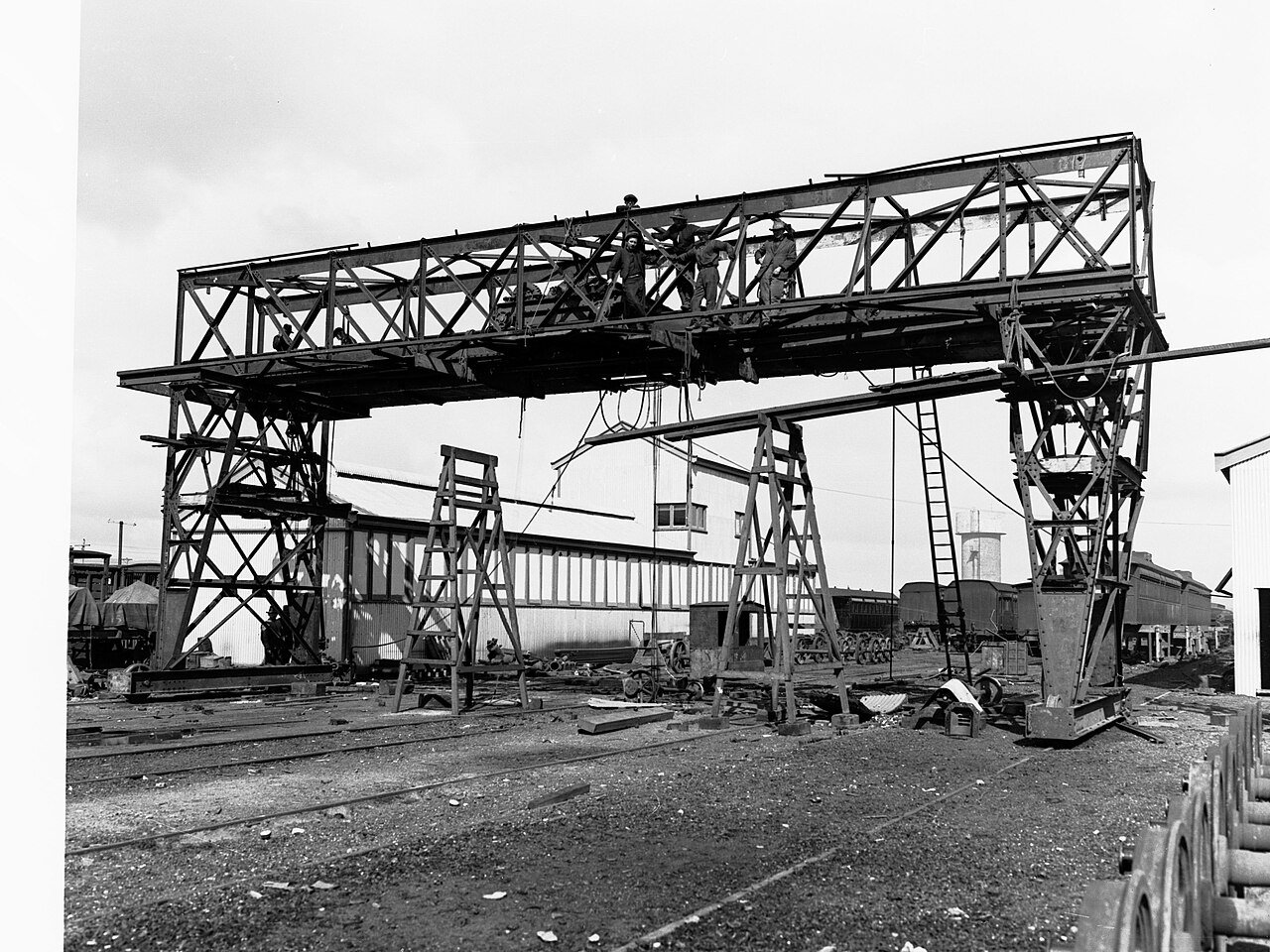 Grúa pórtico antigua en unos talleres ferroviarios con operarios sobre la estructura