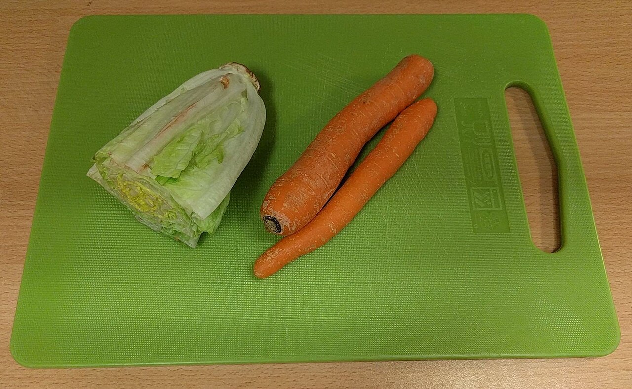 Tabla de cortar verde con lechuga y zanahorias