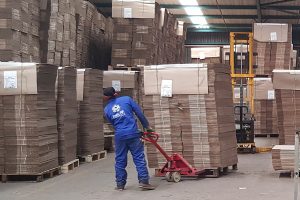 Operario moviendo un palé de cartón con una transpaleta manual