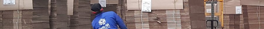 Operario moviendo un palé de cartón con una transpaleta manual