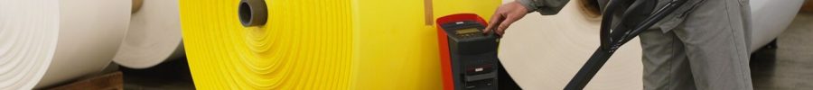 Operario con una transpaleta manual con pesaje moviendo una bobina grande sobre un palé